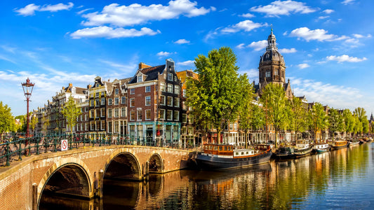 “8K breedbeeldfoto van een historische Amsterdamse gracht met karakteristieke brug, woonboten en grachtenpanden in Amsterdam, Nederland – sfeervolle landmarkfoto voor meubels herstofferen en meubelstoffering in Amsterdam.”