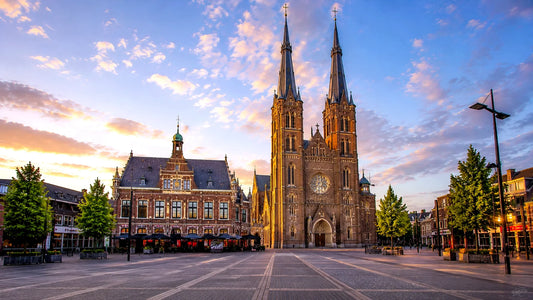 “Breedbeeldfoto van de Heuvelse Kerk en het historische stadsplein in Tilburg, Nederland, bij zonsondergang – hoogwaardige 8K landmarkfoto voor meubels herstofferen en meubelstoffering in Tilburg.”