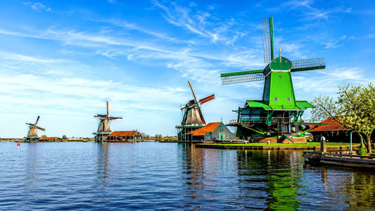 “Breedbeeldfoto van de iconische Zaanse Schans met traditionele groene windmolens aan het water in Zaanstad, Nederland – sfeervolle 8K landmarkfoto voor meubels herstofferen en meubelstoffering in Zaanstad.”